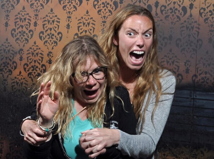 Two terrified women holding each other in a haunted house photo.