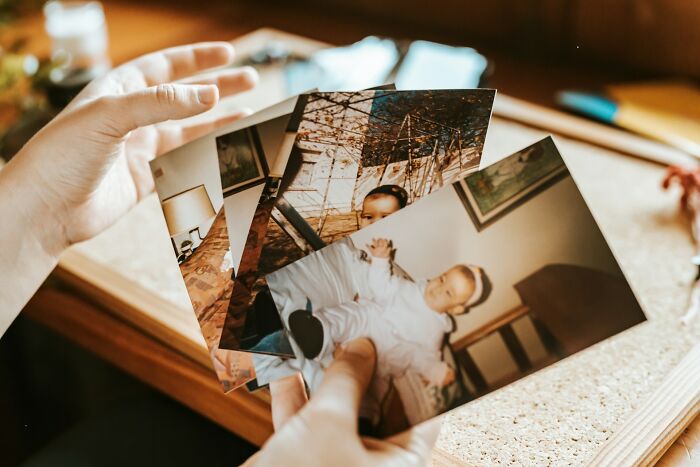 Person holding old family photos that triggered unexpected family feuds