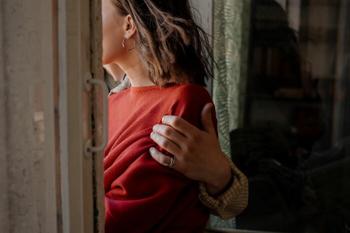 A man puts a supportive arm around a woman in a red sweater, sharing a secret moment together
