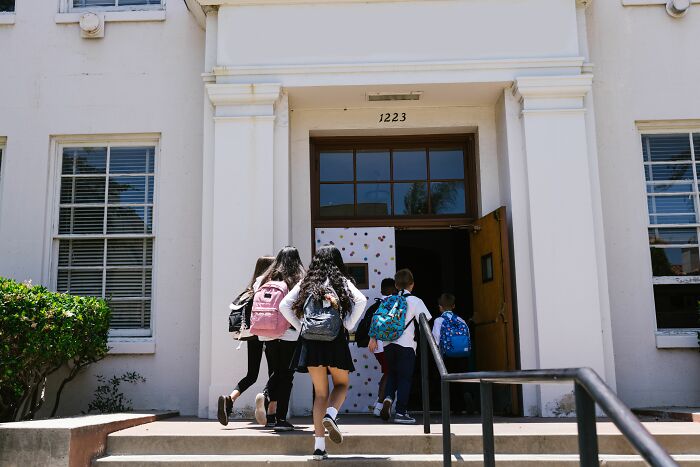 Students entering a school building with backpacks, finding secrets by accident