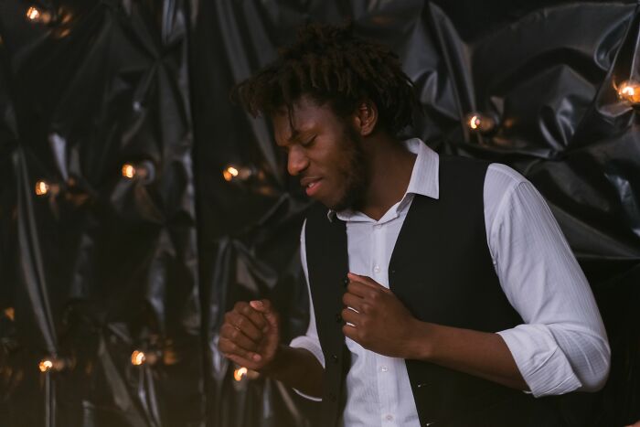 A young man in a vest dances with a joyful expression, sharing the tea of his happiness