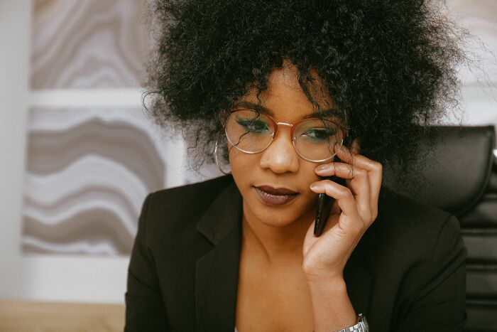 A businesswoman with curly hair talking on a phone, sharing secrets