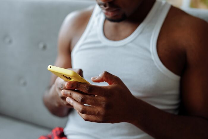 A man looking closely at his mobile phone screen to find secrets shared on the internet