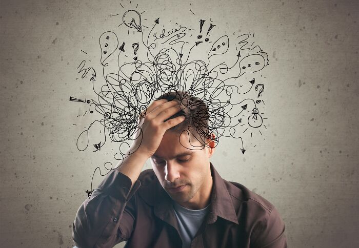 A man with his hand on his head with scribbles over him, representing psychological health problems.