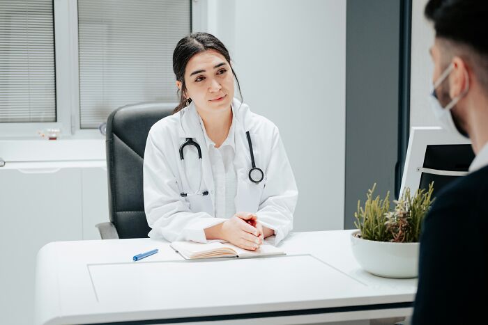 A female doctor speaking with a patient, reflecting how professionals said or did things that lose trust.