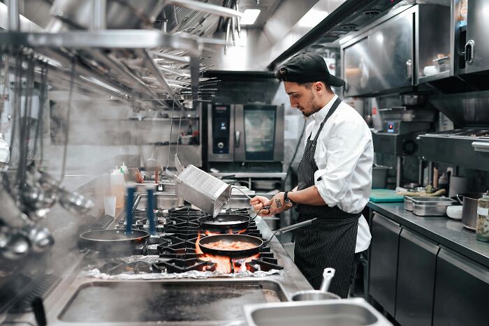 Chef cooking in a busy commercial kitchen, showing industry insiders behind the scenes at restaurants.