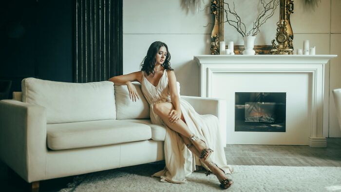 An elegant woman in a gown on a sofa, portraying Hollywood style luxury.