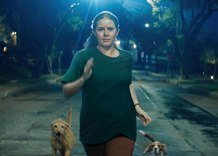 Amy Adams running down a street at night with two dogs, portraying a Hollywood star