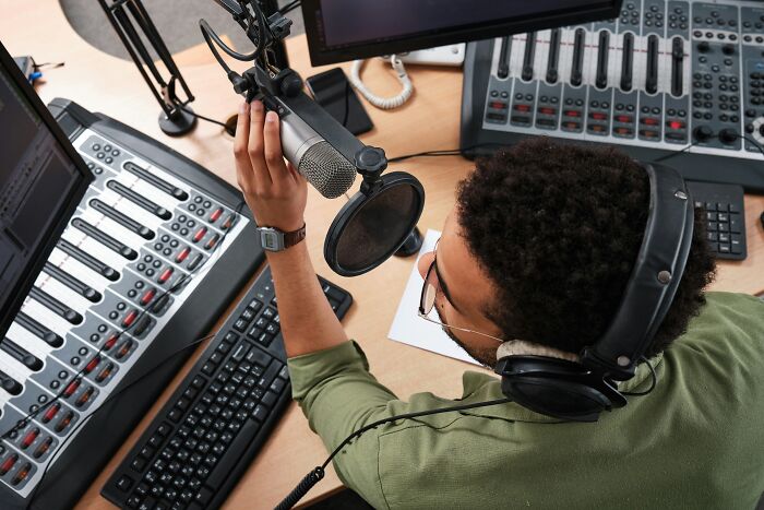 A radio host adjusting a microphone in a sound studio, working as an industry insider.