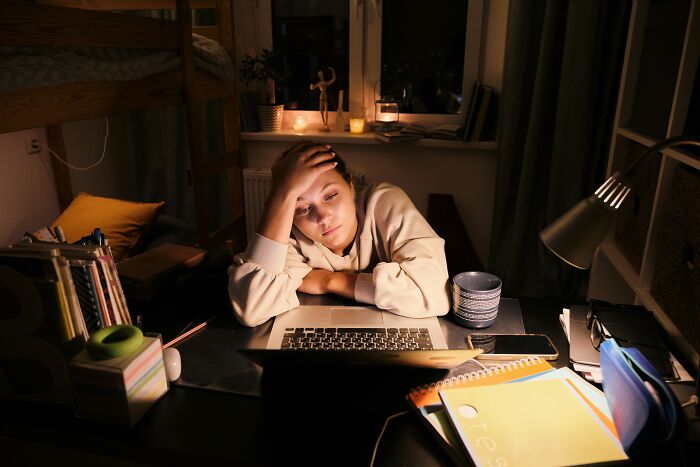 Tired woman leaning over laptop at home, reflecting what industry insiders go through during late hours.