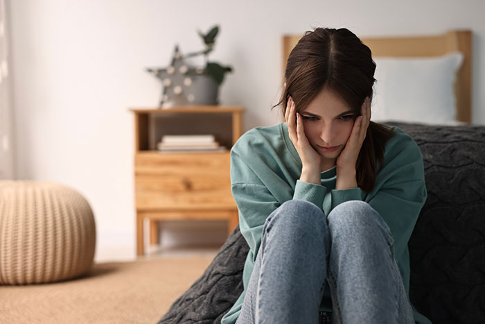 Teen girl sitting on floor looking upset reflecting on lies and friendship Teen girl sitting on floor looking upset reflecting on lies and friendship