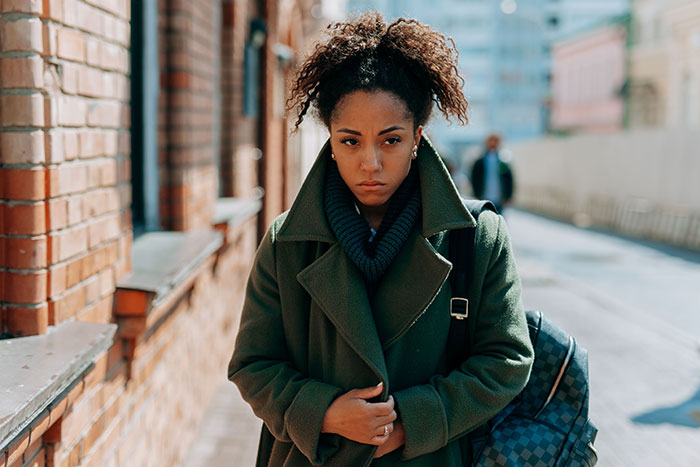 Sad young woman in a green coat walking outdoors, reflecting teen drama Sad young woman in a green coat walking outdoors, reflecting teen drama