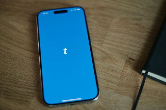 Smartphone showing the Tumblr logo on a wooden table, representing companies people refuse to support