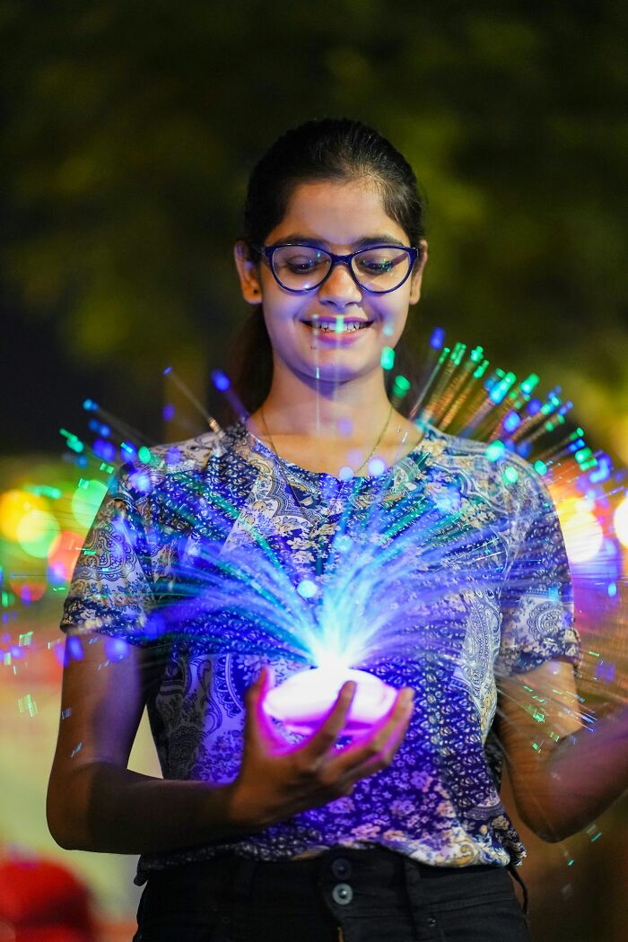 A person holding a glowing fiber optic toy, a weird item received instead of candy while trick-or-treating.