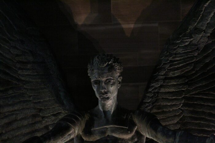Dark angel statue with wings in shadowy ambiance