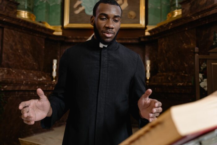 Young pastor praying or preaching inside ornate church