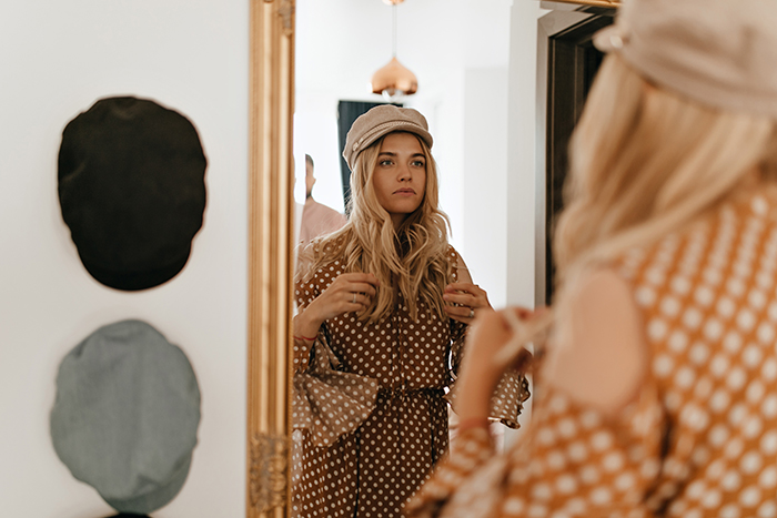 A stylish blonde woman in a polka dot dress looking at her reflection in a mirror. A stylish blonde woman in a polka dot dress looking at her reflection in a mirror.