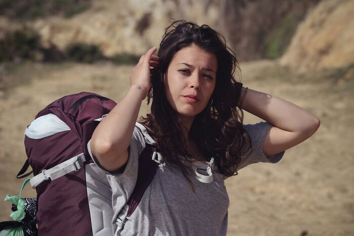 A female hiker holding her hair, listening to her gut feeling during a trek.