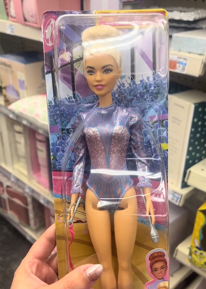 Barbie packaging in a plastic box featuring a gymnastics doll in a glittery outfit on a store shelf.