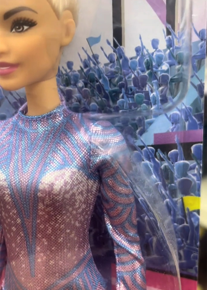Close-up of Barbie packaging showing a blonde doll in a metallic outfit with a crowd illustration behind her.