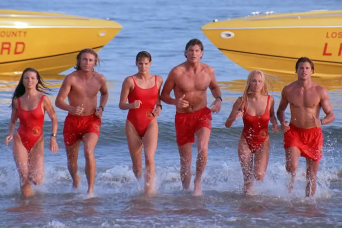 Lifeguards running along the shore in classic red swimsuits ahead of the Hollywood TV reboot.