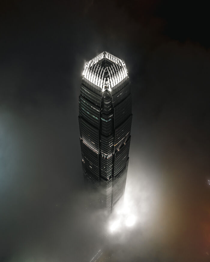 A modern skyscraper rising above a thick layer of clouds, illustrating the beauty of buildings and spaces
