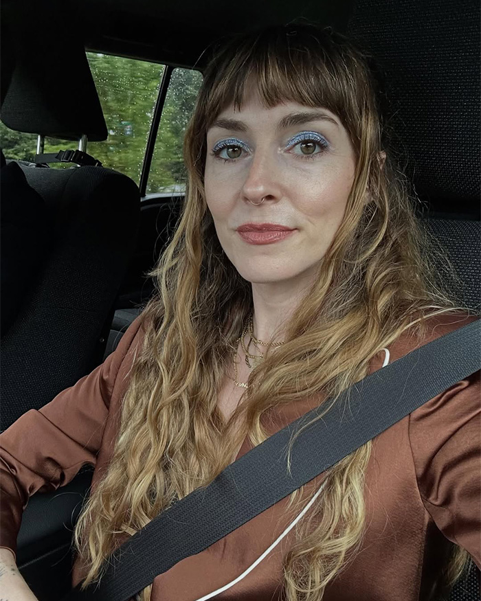 Woman with silver eye makeup wearing a seatbelt in a car