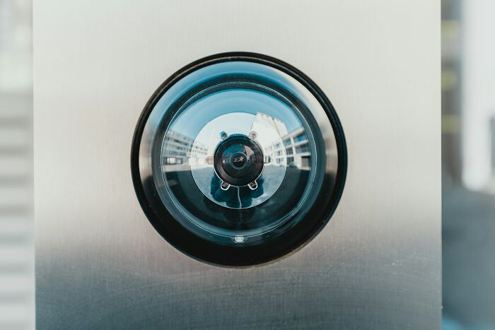 Close-up of a home security peephole camera on a metal door