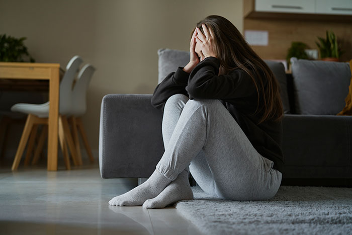 Sad woman sitting on the floor covering her face, from the story of a guy waiting 20 years to tell bestie he loves her. Sad woman sitting on the floor covering her face, from the story of a guy waiting 20 years to tell bestie he loves her.
