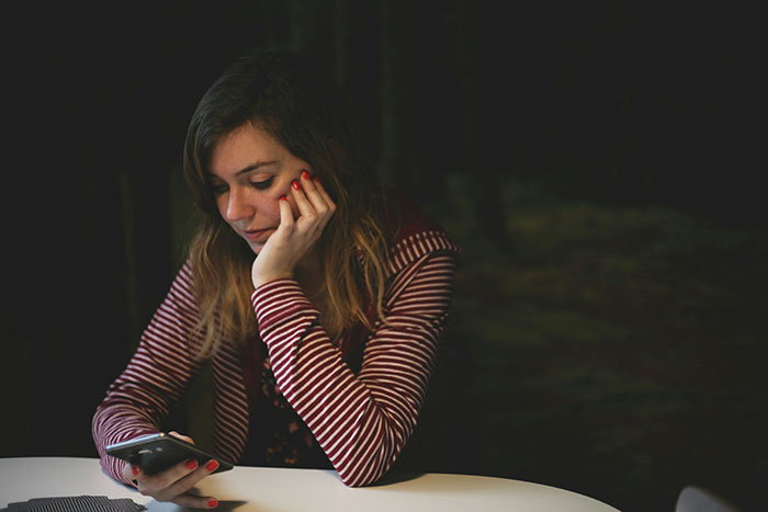 A sad young woman looking at her phone, realizing she has to block her ex-bestie A sad young woman looking at her phone, realizing she has to block her ex-bestie