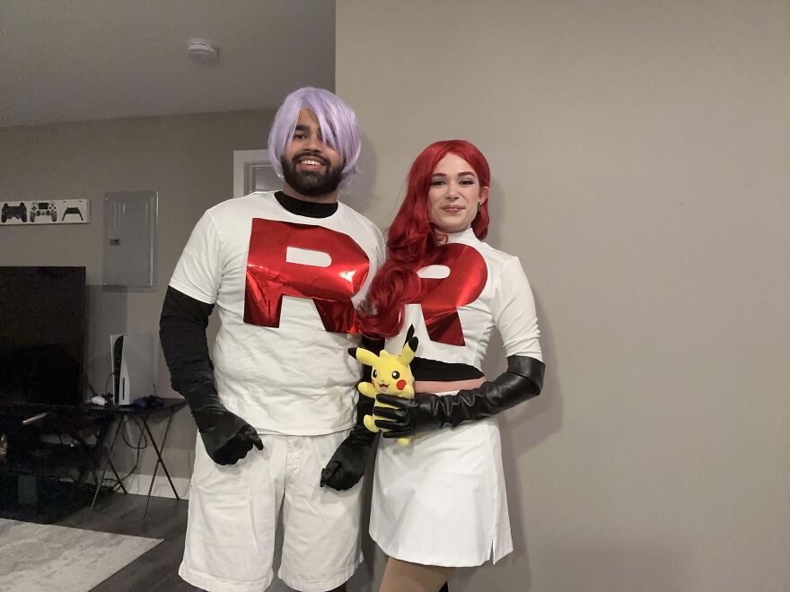 Couple posing together in matching Team Rocket Pokemon Halloween costumes.