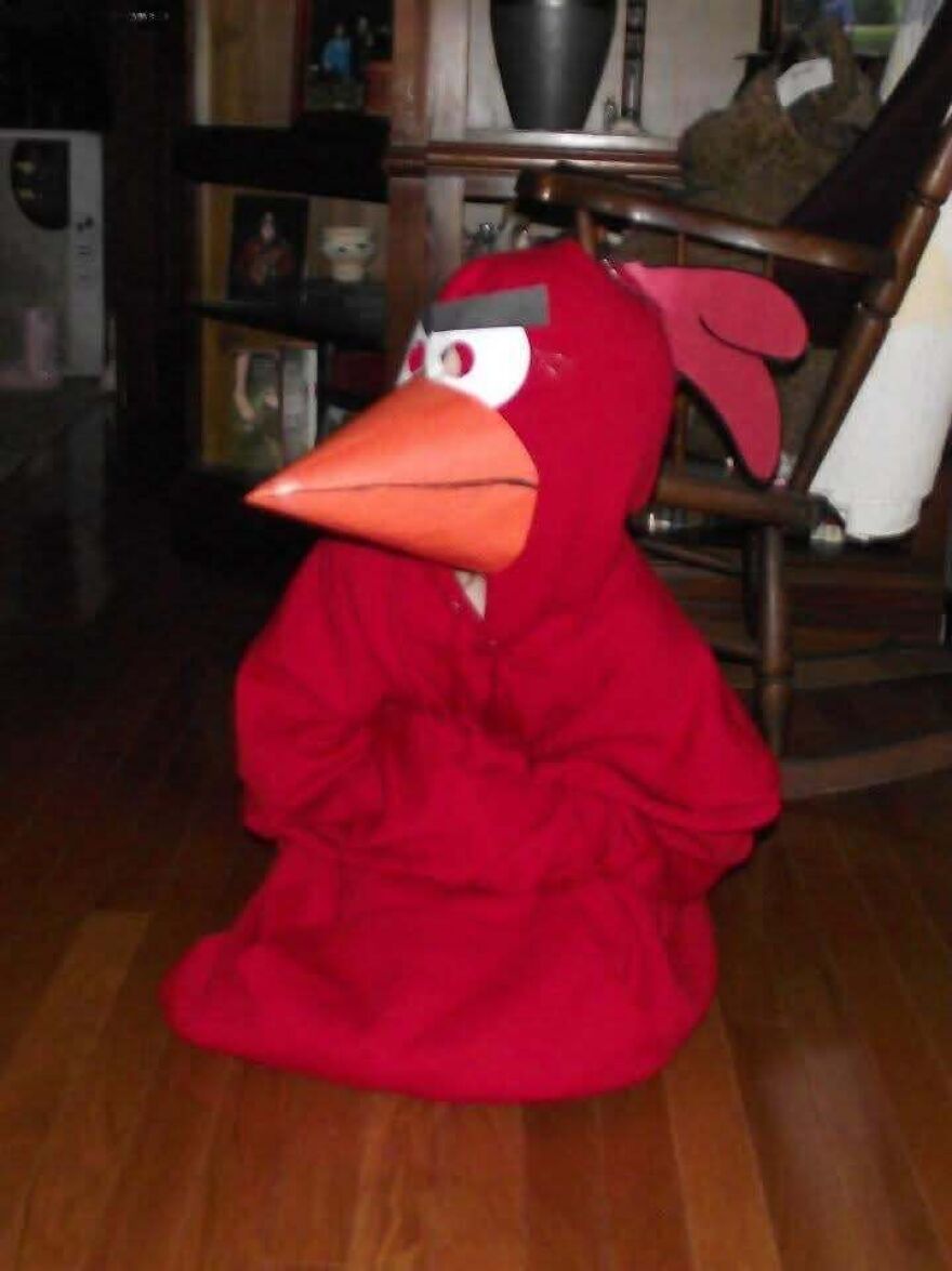 Child sitting indoors wearing a homemade red Angry Bird Halloween costume.