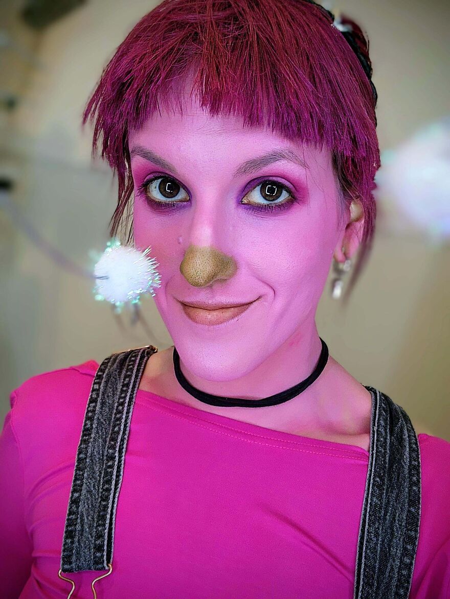 Person with bright pink face makeup and hair dressed in a creative Halloween costume.