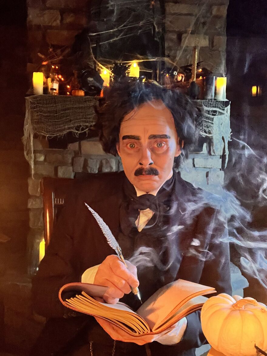 Person dressed up as Edgar Allan Poe in an impressive Halloween costume writing in a book.