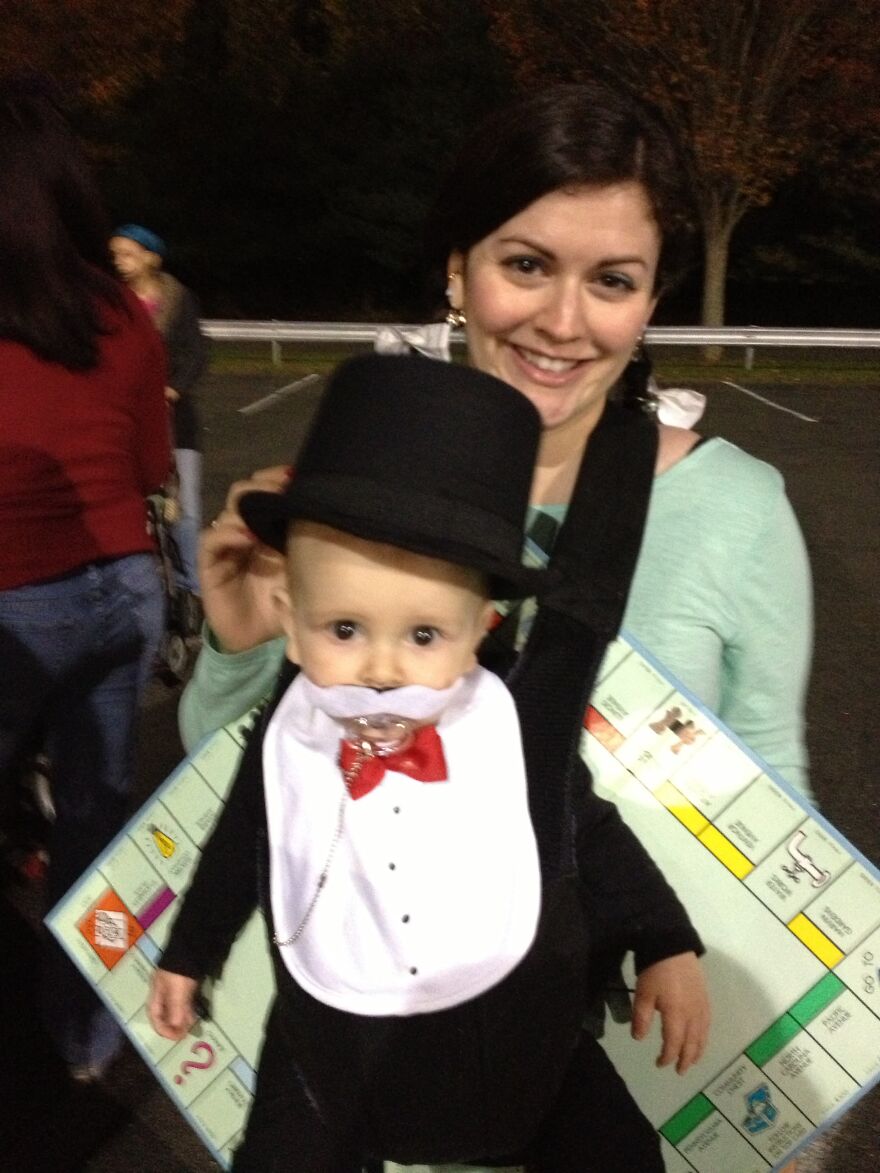 Baby in Monopoly man Halloween costume carried by mother in board costume