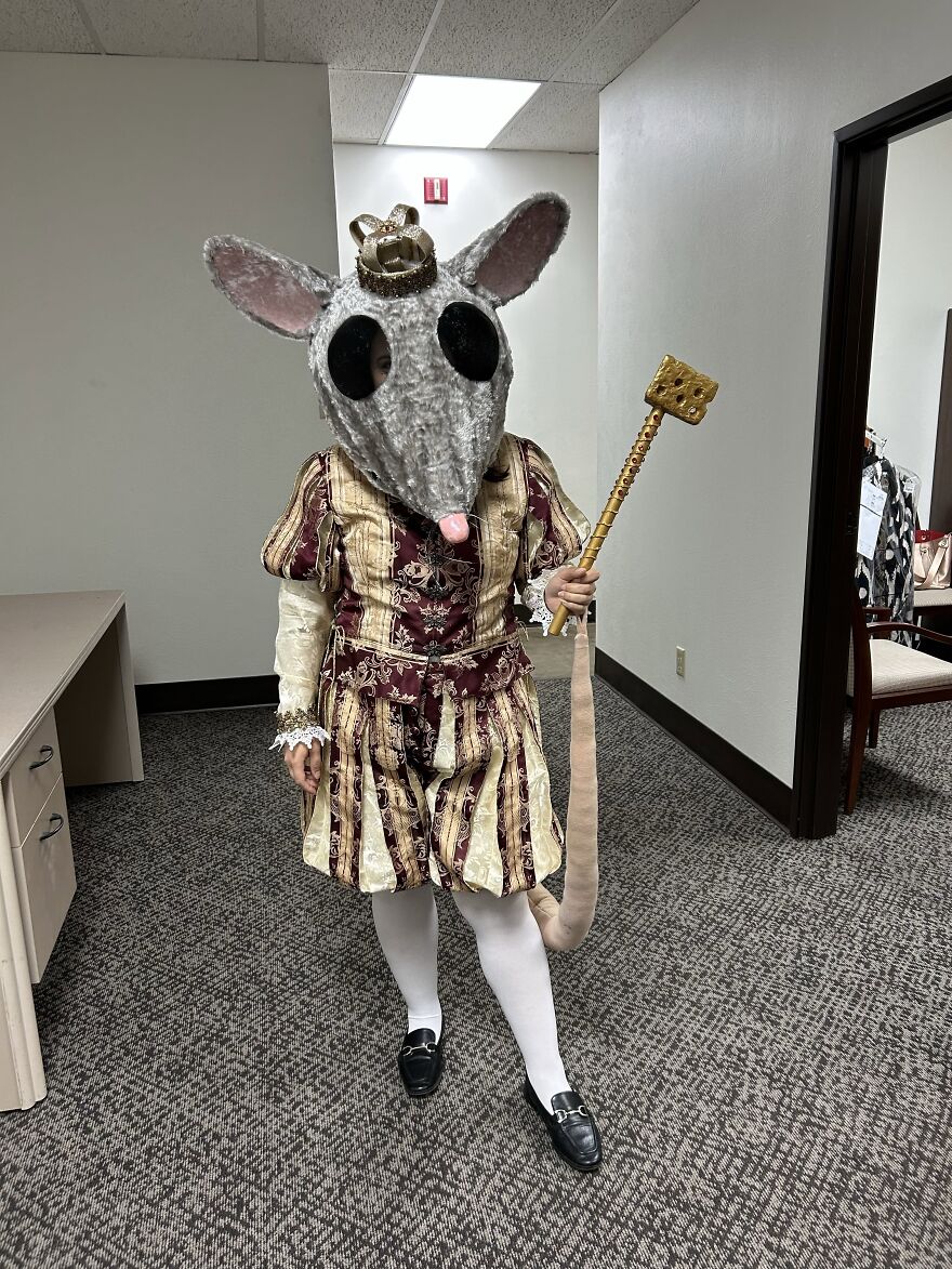 Person wearing elaborate mouse king Halloween costume with mask and cheese wand