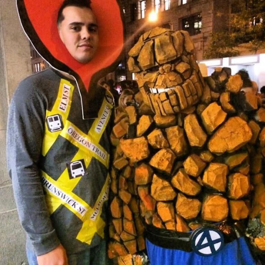Two men wearing unique Halloween costumes posing as a map pin and superhero character outdoors