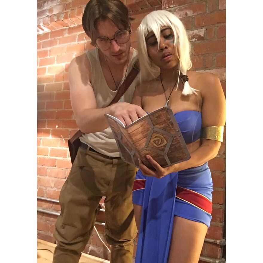 Couple dressed up in detailed Atlantis movie Halloween costumes reading a prop book together.