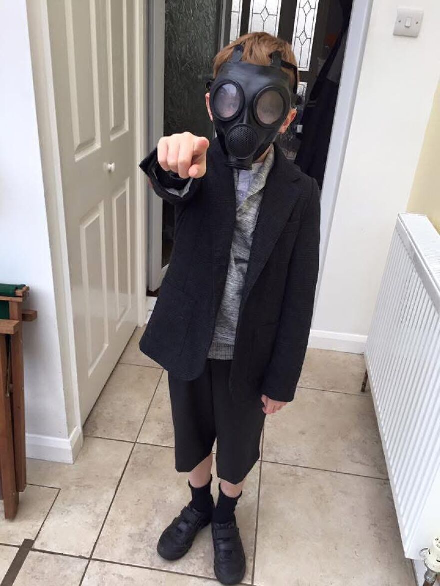 A boy wearing a gas mask and suit jacket posing in a creative Halloween costume