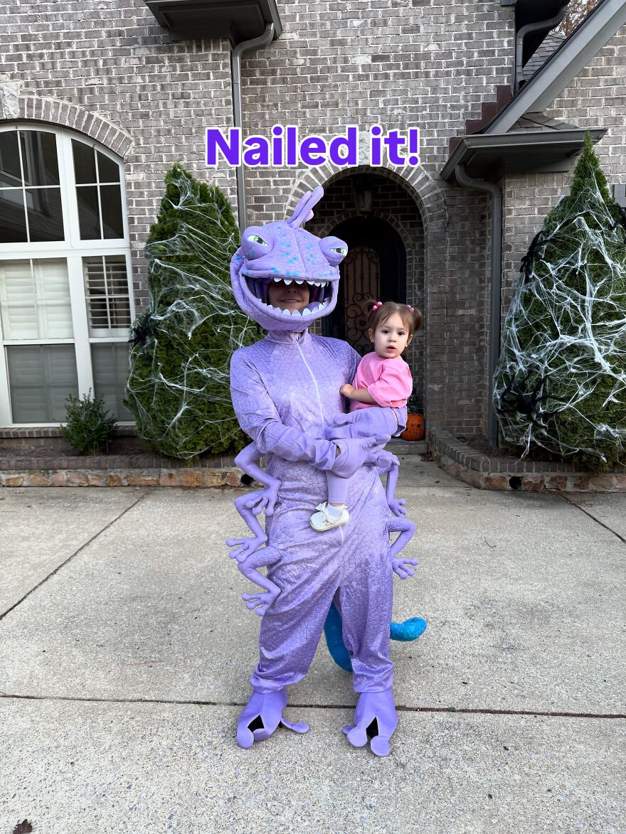 A person in a purple Randall monster suit holding a child in a fun Halloween costume
