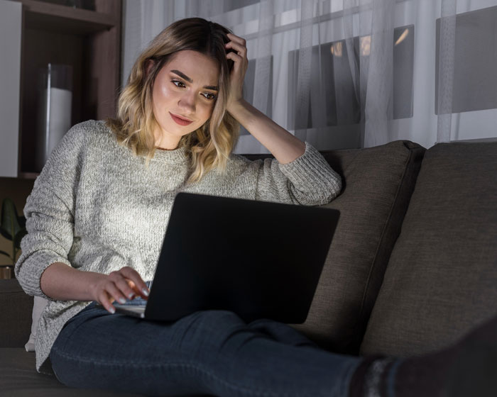 Woman sitting on couch looking shocked at her laptop as she dumps cheater BF Woman sitting on couch looking shocked at her laptop as she dumps cheater BF