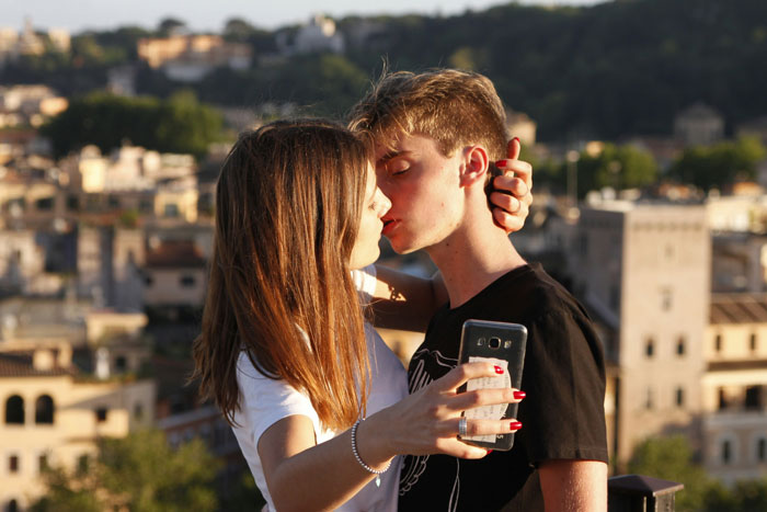 A couple kissing while the woman takes a selfie, representing a cheater BF and his mistress. A couple kissing while the woman takes a selfie, representing a cheater BF and his mistress.