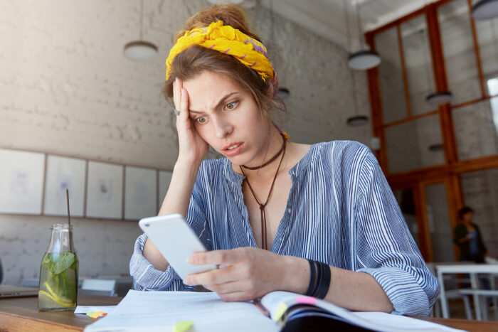 A worried woman checks her phone to use a flight tracker app
