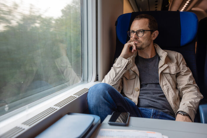 Thoughtful guy sitting on a train, representing a fake flight to Italy story