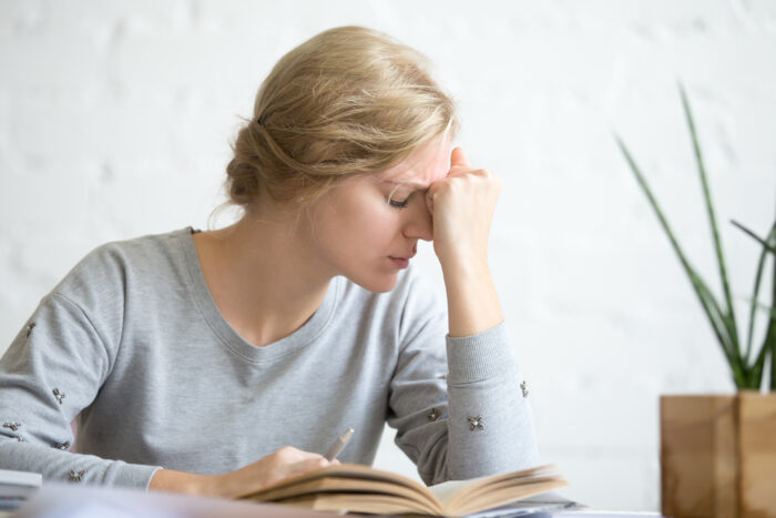 Stressed woman holding her head while working, illustrating how gf checks the flight tracker on a guy.