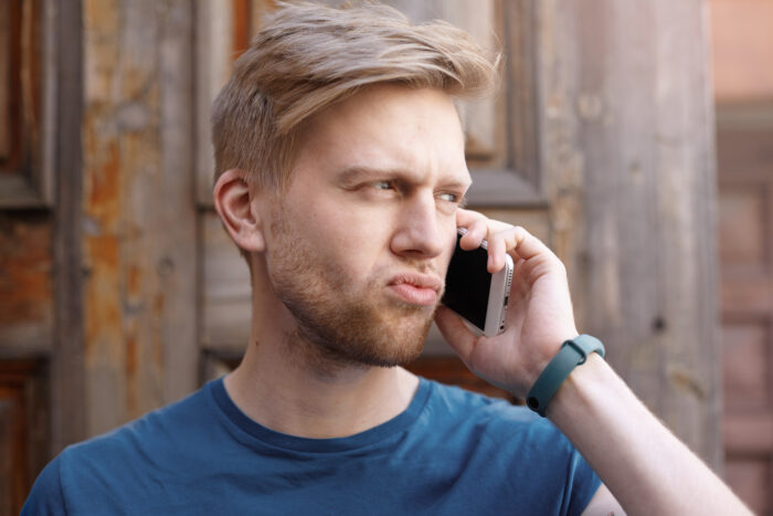 A guy making a confused expression while talking on his phone, related to an imaginary flight to Italy story.