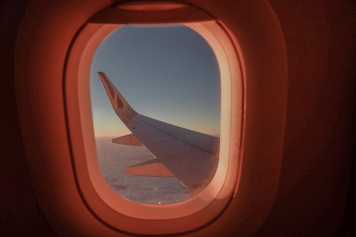 View from an airplane window over clouds during a flight to Italy at sunset