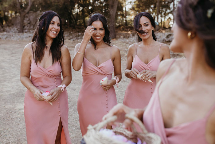 Bridesmaids in matching pink dresses at outdoor wedding event Bridesmaids in matching pink dresses at outdoor wedding event