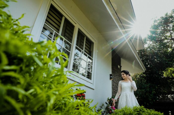 Bride in wedding dress posing outside house in sunlight Bride in wedding dress posing outside house in sunlight