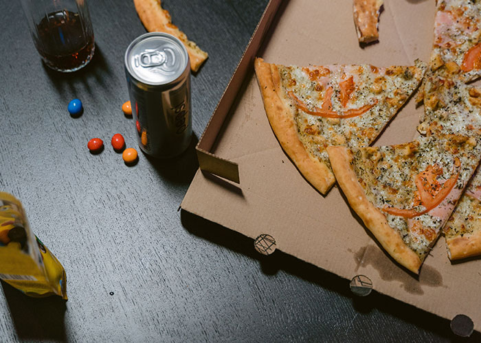 Leftovers of a messy pizza and soda cans after a rowdy bridezilla ruins hotel rooms party